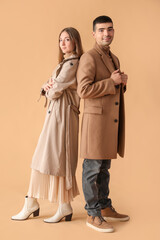 Fashionable young couple in autumn clothes on beige background