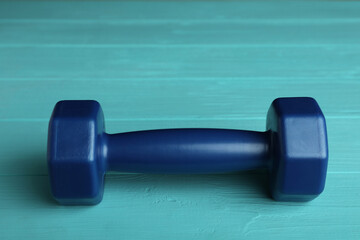 Blue vinyl dumbbell on turquoise wooden table