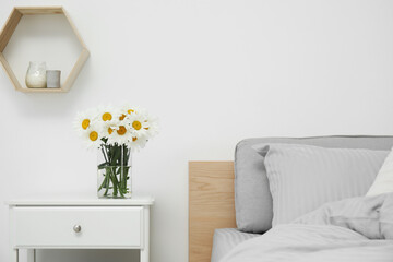 Bouquet of beautiful daisy flowers on nightstand in bedroom