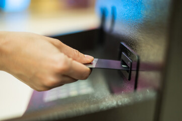 Faceless woman inserts bank card at ATM. 