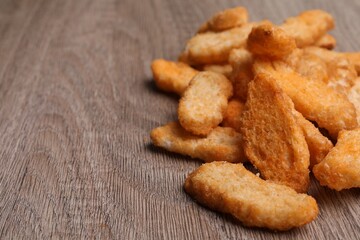 Heap of crispy rusks on wooden table, closeup. Space for text