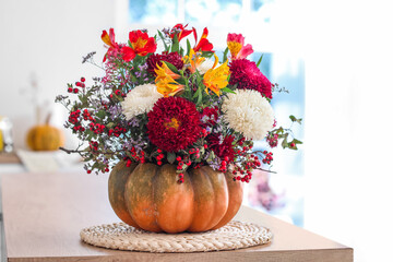Pumpkin with autumn flowers on counter in kitchen, closeup