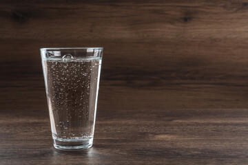 Glass of soda water on wooden table. Space for text