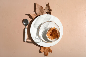 Autumn table setting with fallen leaves on beige background