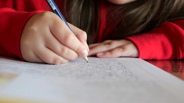 Homework.schoolgirl does her homework. child writes with a pencil in a notebook.Study and education concept. Close-up pencil in a childs hand writes words in a notebook. 4k footage - Powered by Adobe