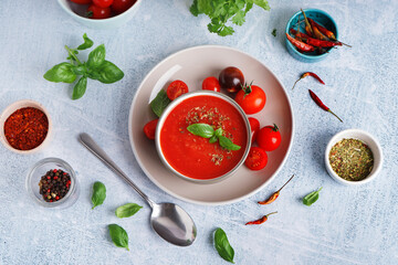 Composition with bowl of tasty tomato soup and spices on light background