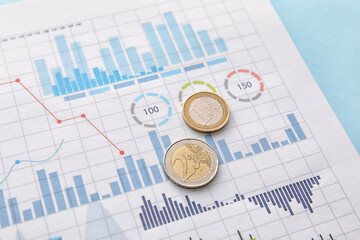 Euro coins with diagrams on blue background. Exchange rate concept