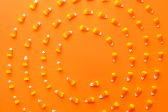 Frame made of Halloween candy corns on orange background