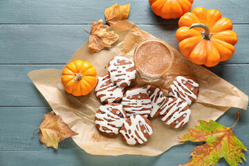 Baking paper with Halloween mummy cookies, glass of cocoa, pumpkins and leaves on color wooden background