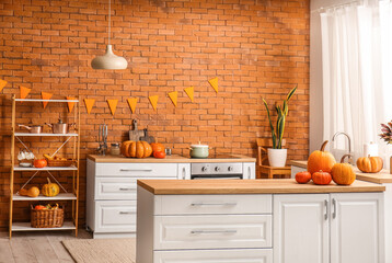 Interior of modern kitchen with Halloween pumpkins, counters and shelving unit