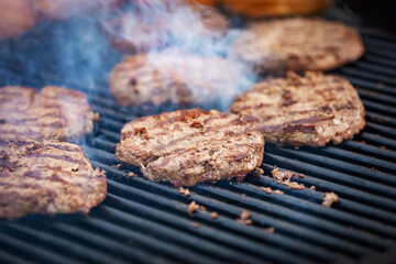 Grilling meat cutlets for burgers. Fast food or street food. Steel grill grate, cutlet in the...