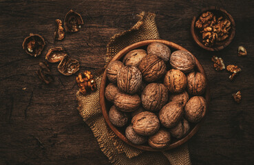 Fresh raw walnuts in bowl, autumn food background, nuts harvest. Old rustic wooden background, top view