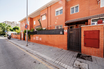 Facades with urban single-family homes with exposed clay-colored brick and black metal railings