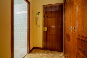 Entrance hall of an urban residential home with oak parquet flooring, mahogany cabinets and doors, and yellow painted walls