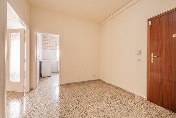 Empty hall with old terrazzo floor and white carpentry and access to several rooms