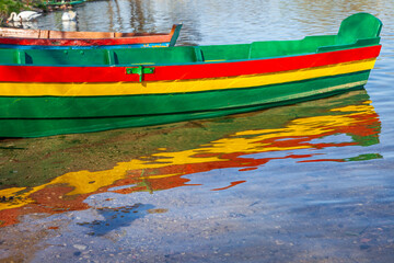 Boats with lithuanian flag colors at lake shore in morning, Lithuania