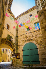 Narrow street and old stone facade with colorful flags hanging from the walls in the medieval village of Saint Montan, in the South of France (Ardeche)