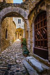 Fototapeta premium Narrow paved street and old wooden door in the medieval village of Saint Montan in Ardeche. France