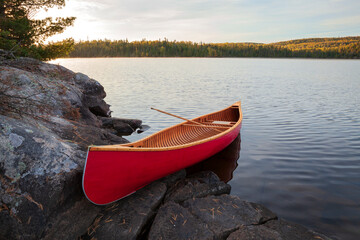 Red wood canoe on rocky island in the Boundary Waters on a bright autumn morning