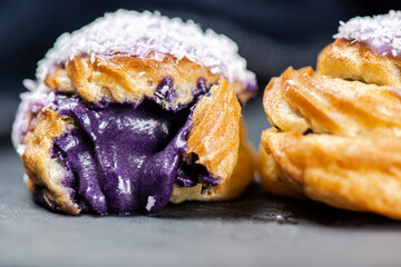 Home-made ube cream puff with purple-colored white chocolate and coconut, also known as a Profiterole.