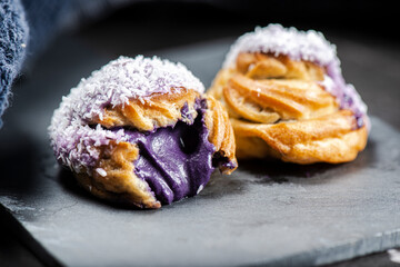 Home-made ube cream puff with purple-colored white chocolate and coconut, also known as a...
