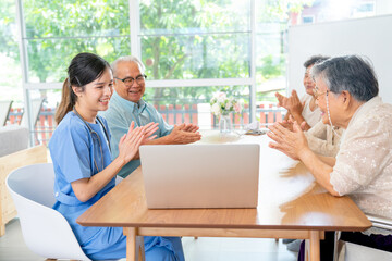 Asian senior man and woman enjoy to talk and fun with activity of nurse or doctor during teach with laptop on table in living room of clinic or hospital.
