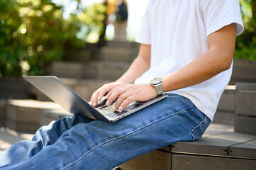 Fototapeta premium 屋外で座りながらパソコンを操作する男性