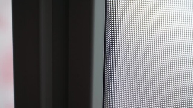 Double-glazed window of a plastic door with opaque glass close-up in the dark. Textured window in a plastic case. Smooth camera movement. White front doors