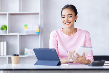 Young business Asian woman working in note and tablet the home workplace, reading and taking notes on the paper, accounting, tax, Financial, Business concept