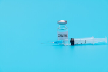 Syringe and coronavirus vaccine on blue background