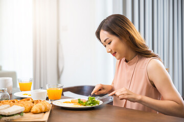 Obraz na płótnie Canvas Asian young woman sitting kitchen table food having eating healthy breakfast at home, female eat fresh breakfast served food with beverage before go to work in the morning at home