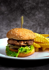 Craft beef burger and french fries on black background.