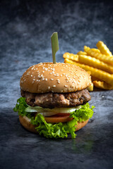 Craft beef burger and french fries on black background.