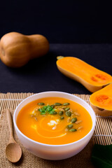 Butternut squash pumpkin soup in bowl on black background, Homemade food in autumn season