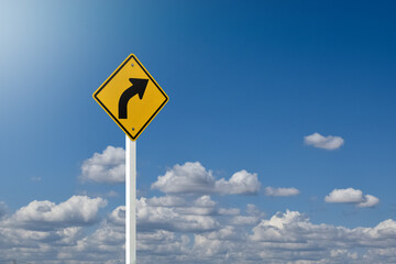 Traffic sign; right arrow curve sign on white pole by the main road with blue sky background, soft...