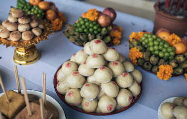 pile of buns in a tray are on the table with food and fruit to offer to the deceased according to Buddhist beliefs.