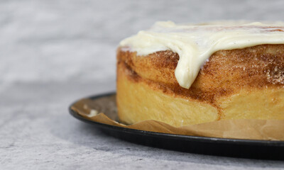 close up of buttercream frosting on cinnamon roll cake, white background, grey marble table
