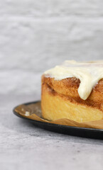 close up of buttercream frosting on cinnamon roll cake, white background, grey marble table