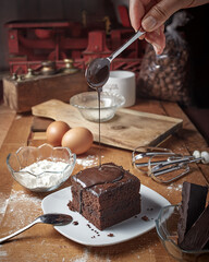 pour a melted chocolate on a piece of steamed brownies cake or brownies kukus delicious cake  - obrazy, fototapety, plakaty