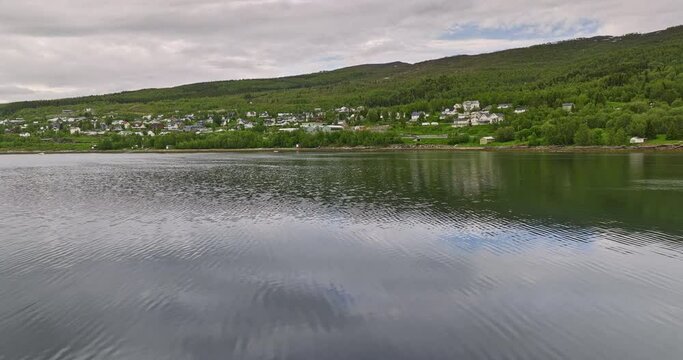 Finnsnes Norway v1 low level drone flyover inlet above water surface towards the shore capturing residential neighborhood with scandinavian norwegian homes - Shot with Mavic 3 Cine - June 2022
