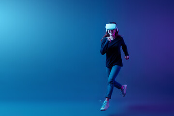 Asian woman wearing VR headset with experience playing video game and running and jumping...