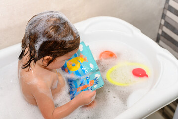 Girl looking at a book with numbers in the bathtub