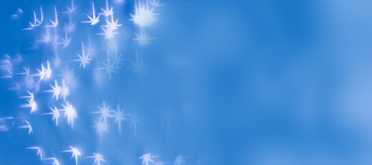 Christmas or New Year abstract magic lights background, white stars bokeh on blue as winter holiday banner Xmas mood aesthetic photo, blurred effect, celebration illumination, starry sky