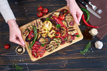 Grilled vegetables mix on a wooden cutting board - zucchini eggplant onions corn mushroom tomato