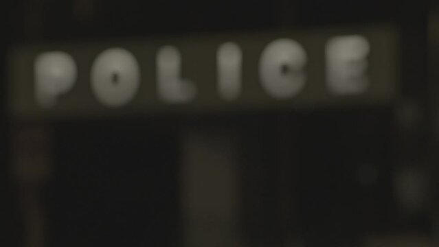 A static shot of a police board which is illuminating at night. the video is transforming from blur to clear 