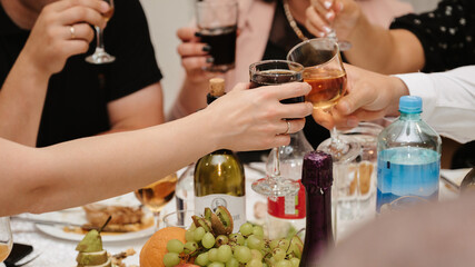 group of friends clink glasses with wine and celebrate the holiday at a festive table