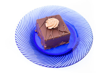 Amandine cake, square portion, on a blue glass plate, isolated on white