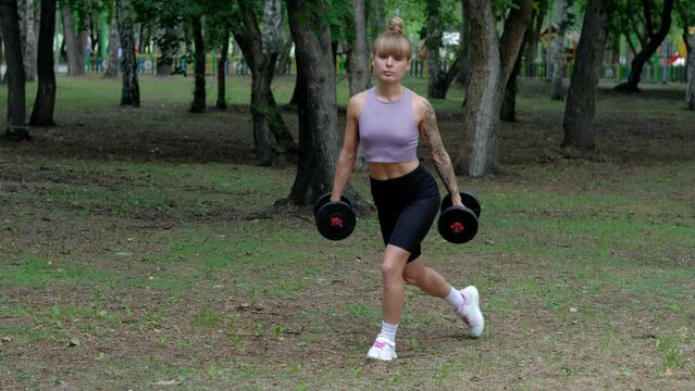 Blondie fitness woman training in the park squat with dumbbells.