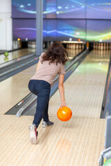 A woman throws a ball into a bowling alley. Paths with balls and pins for bowling. A fun game for the company.