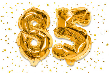 The number of the balloon made of golden foil, the number eighty five on a white background with...